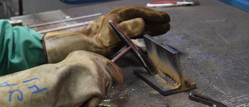 Hands in welding cloves working with metal tools